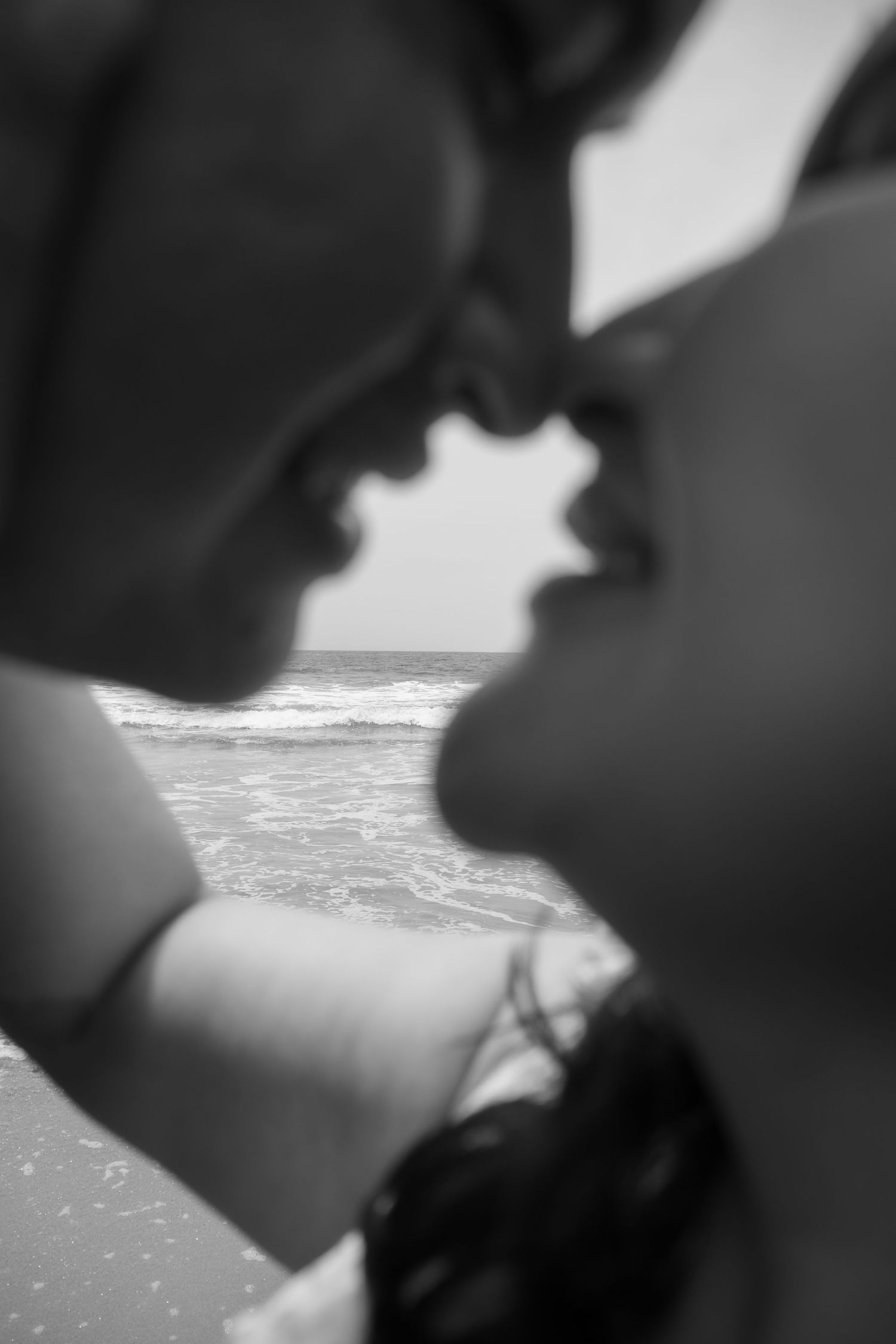 Close-up silhouette view of hands against ocean waves and sunlight.