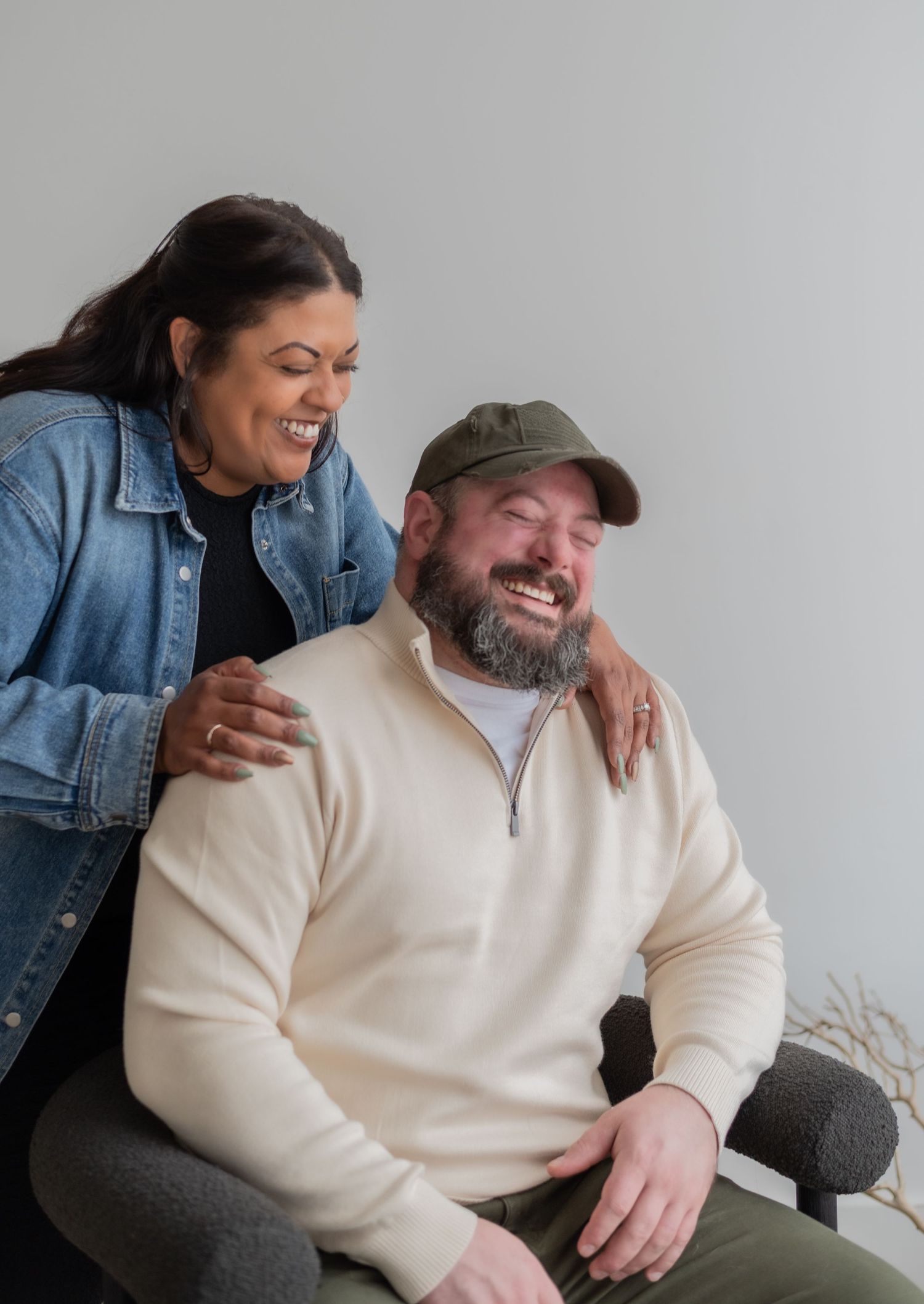 A couple sharing laughter while sitting together in a bright studio space.