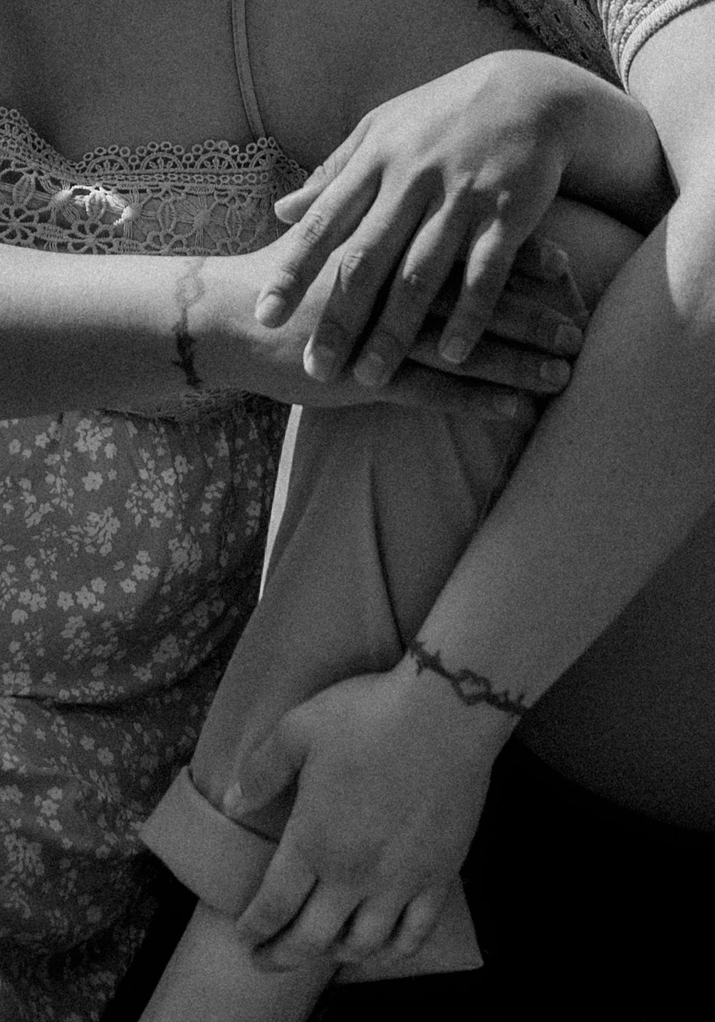 Black and white close-up of hands gently resting on floral fabric clothing.
