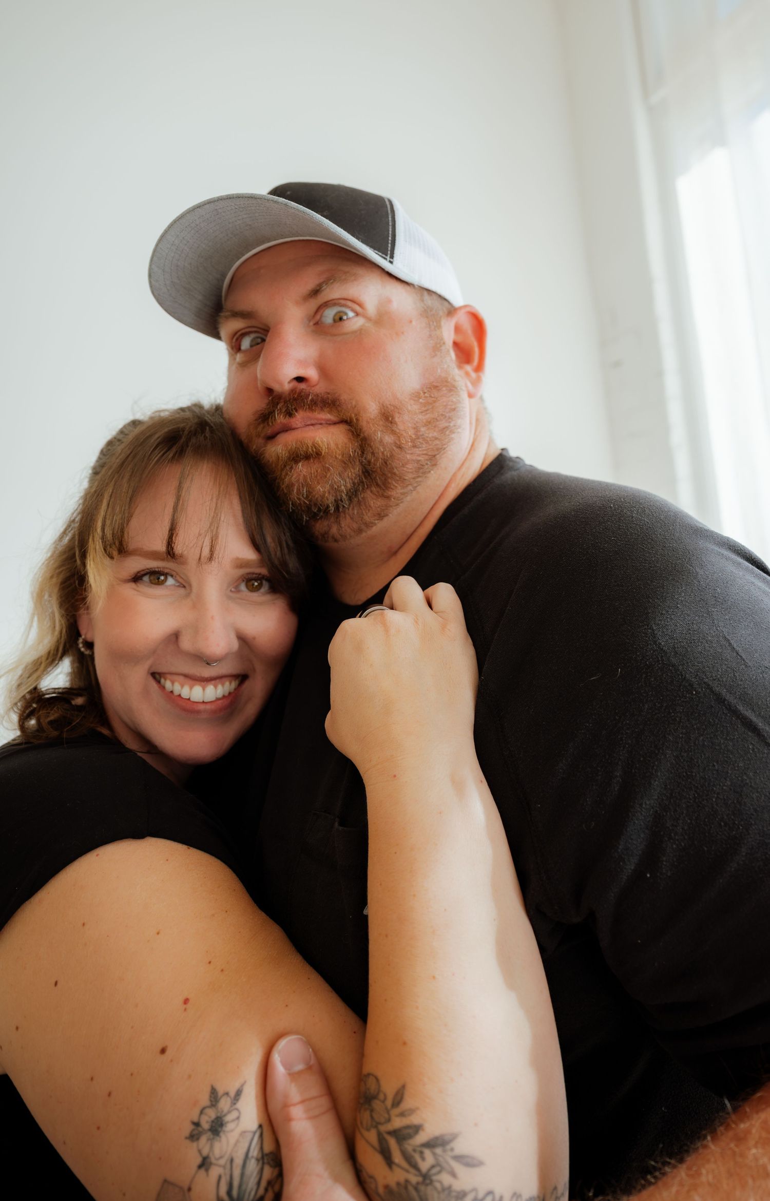 A couple shares a playful moment together in a bright indoor setting.