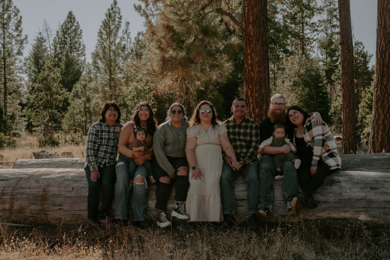Large group portrait session in a forest setting with evergreen trees.