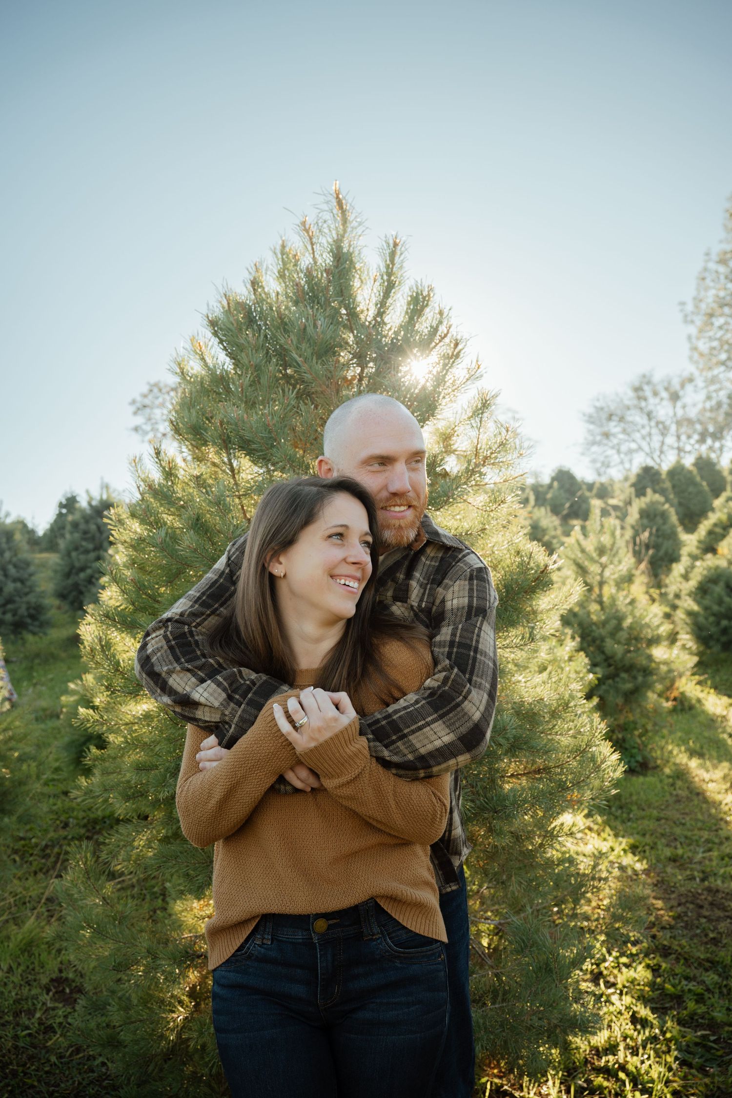 Intimate moment captured at sunset among evergreen trees at Christmas tree farm.