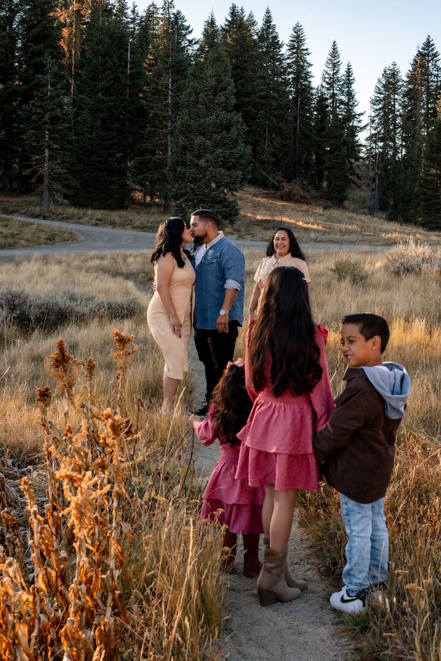 Group walking together on a scenic mountain path with golden grass and evergreens.