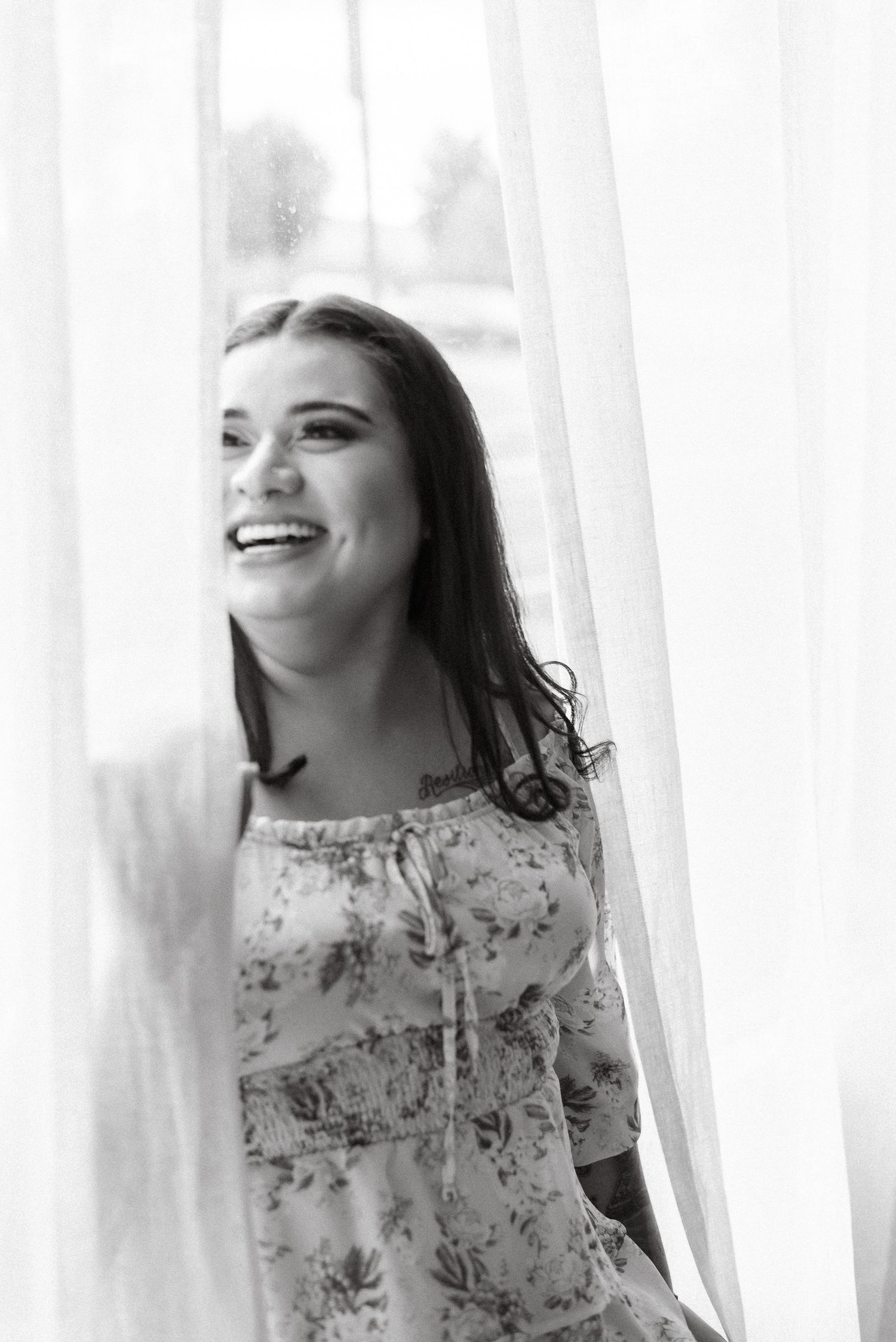 Black and white portrait series showing joyful expressions through sheer white curtains.