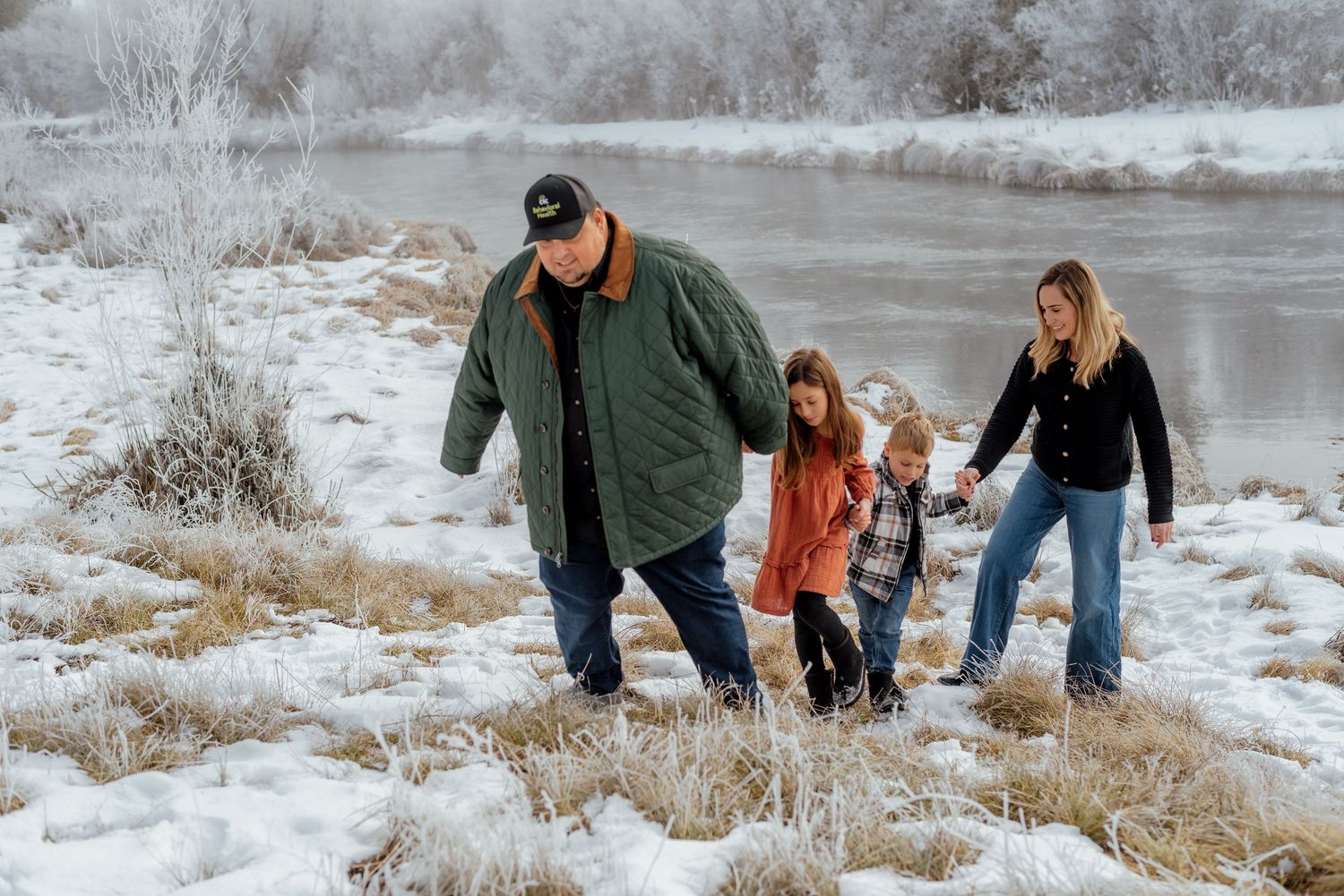 Group walks together along a snowy riverbank on a winter day.