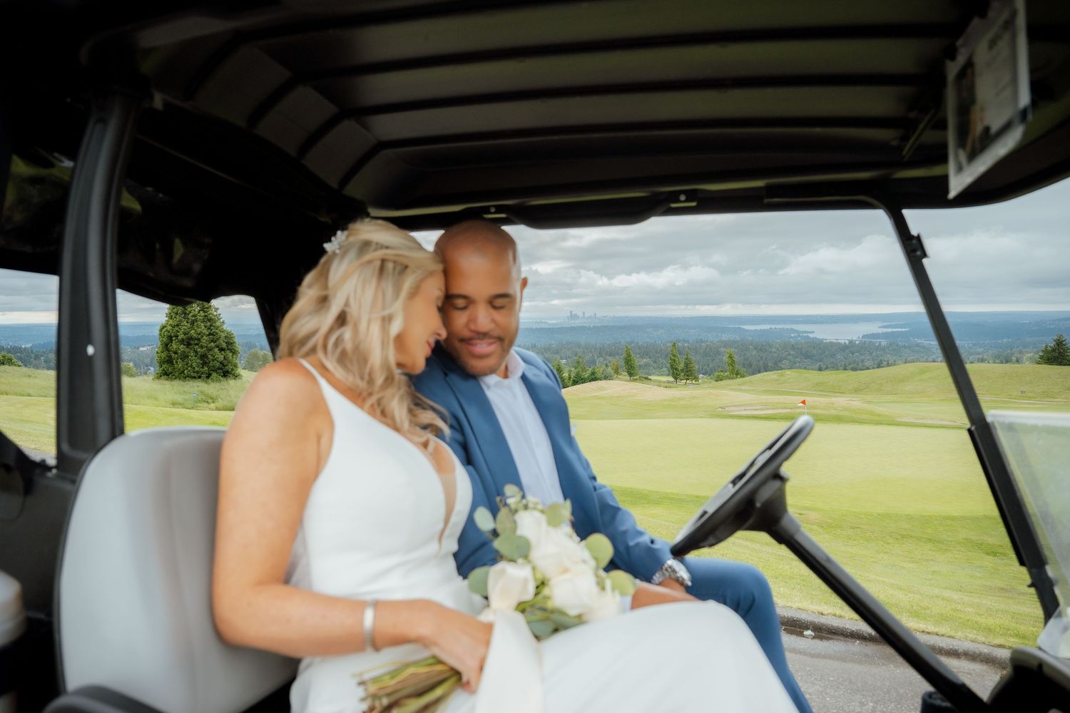 Happy couple riding in golf cart on scenic course during wedding day celebrations.