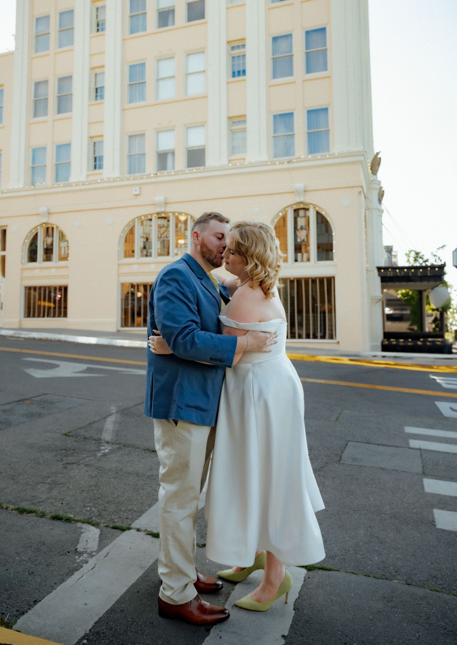 Romantic moment shared on city street corner near classic architecture.
