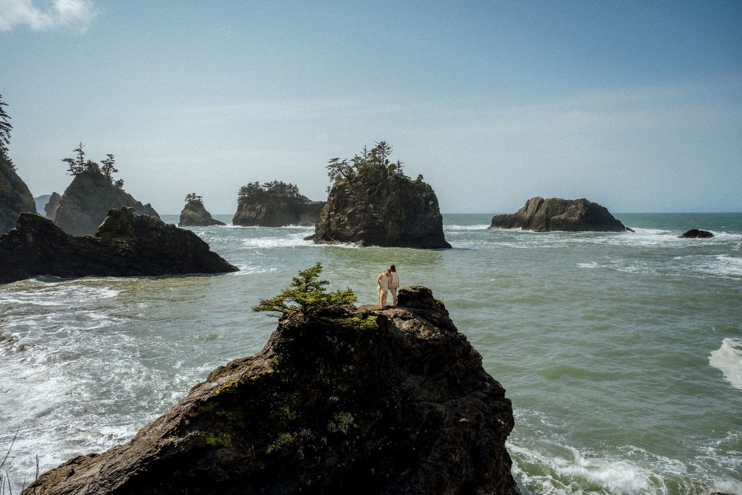 Panoramic view of rugged coastline with rocky outcrops and churning ocean waves.