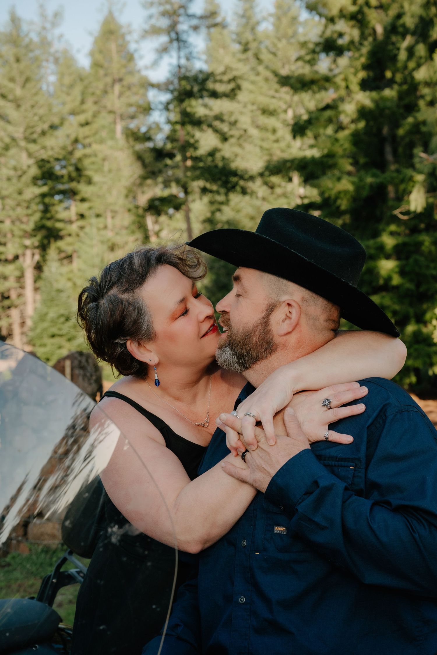 A romantic photoshoot in a forest setting with pine trees in the background.
