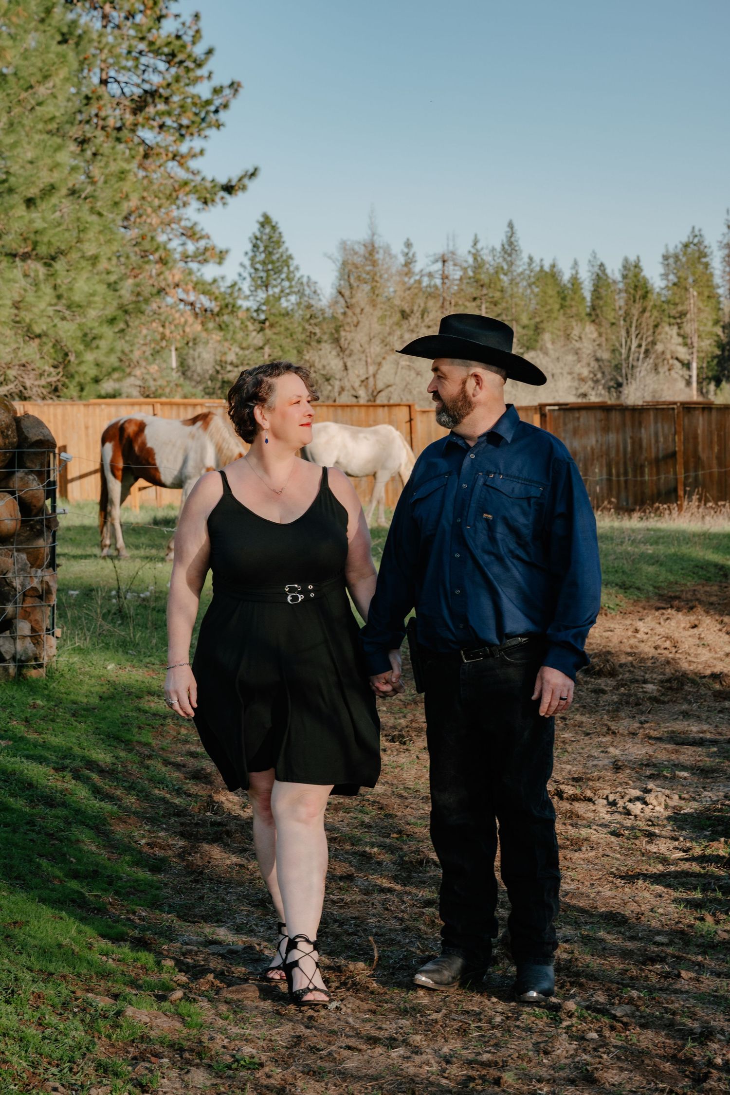 A couple taking a romantic stroll through a rural landscape with trees.