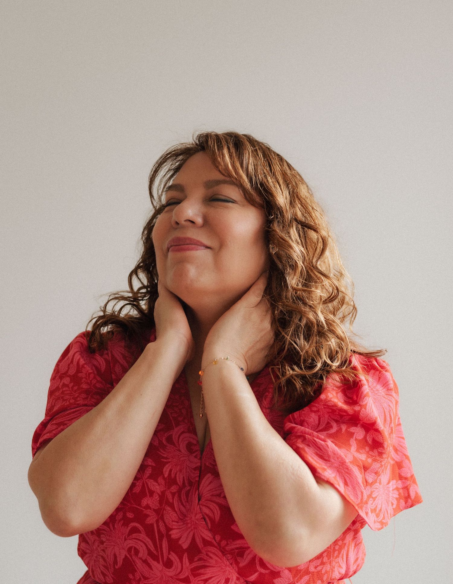 Expressive portrait series showing joyful poses in red dress against white wall.