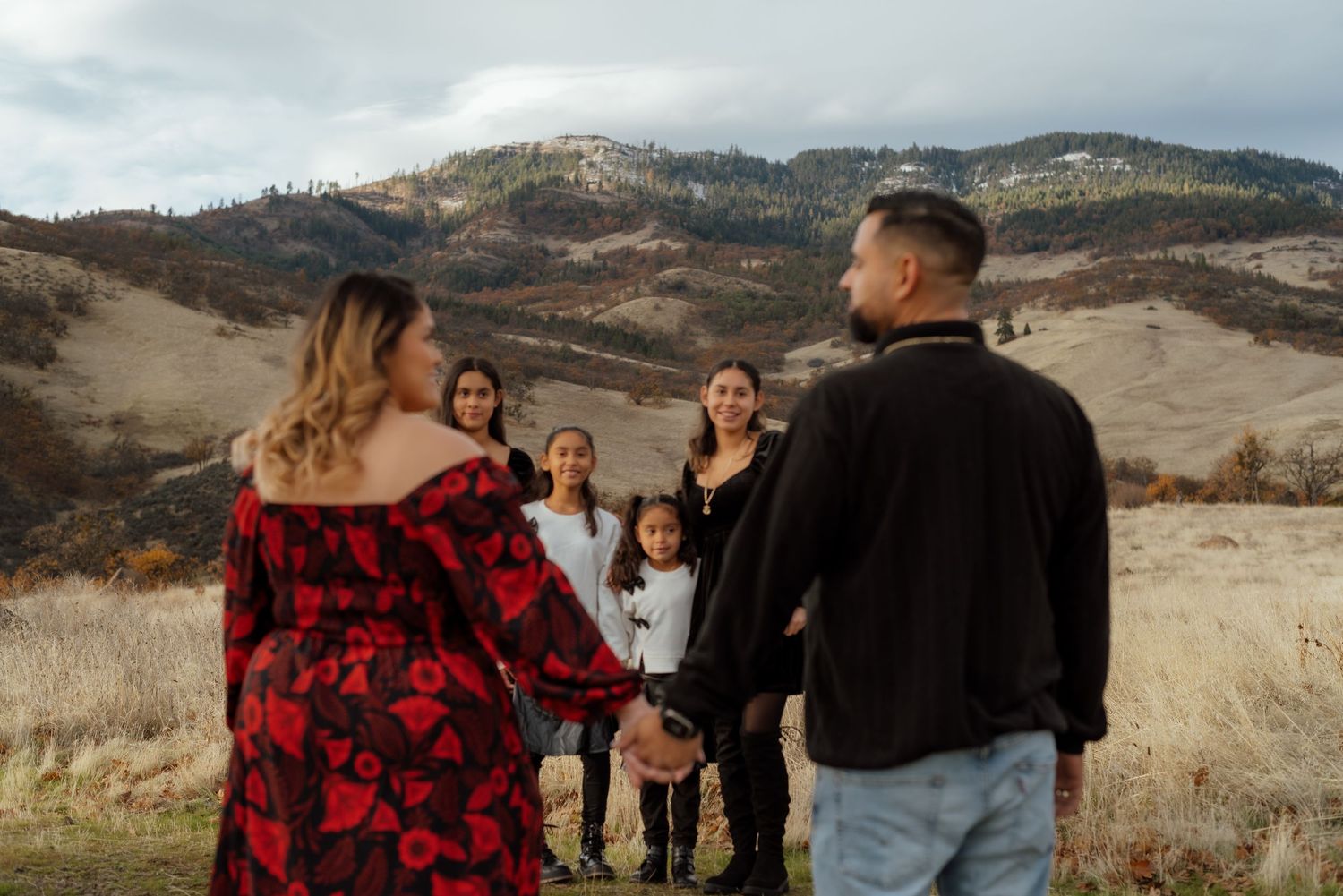 Family gathering for photos in a mountain field with autumn colors.