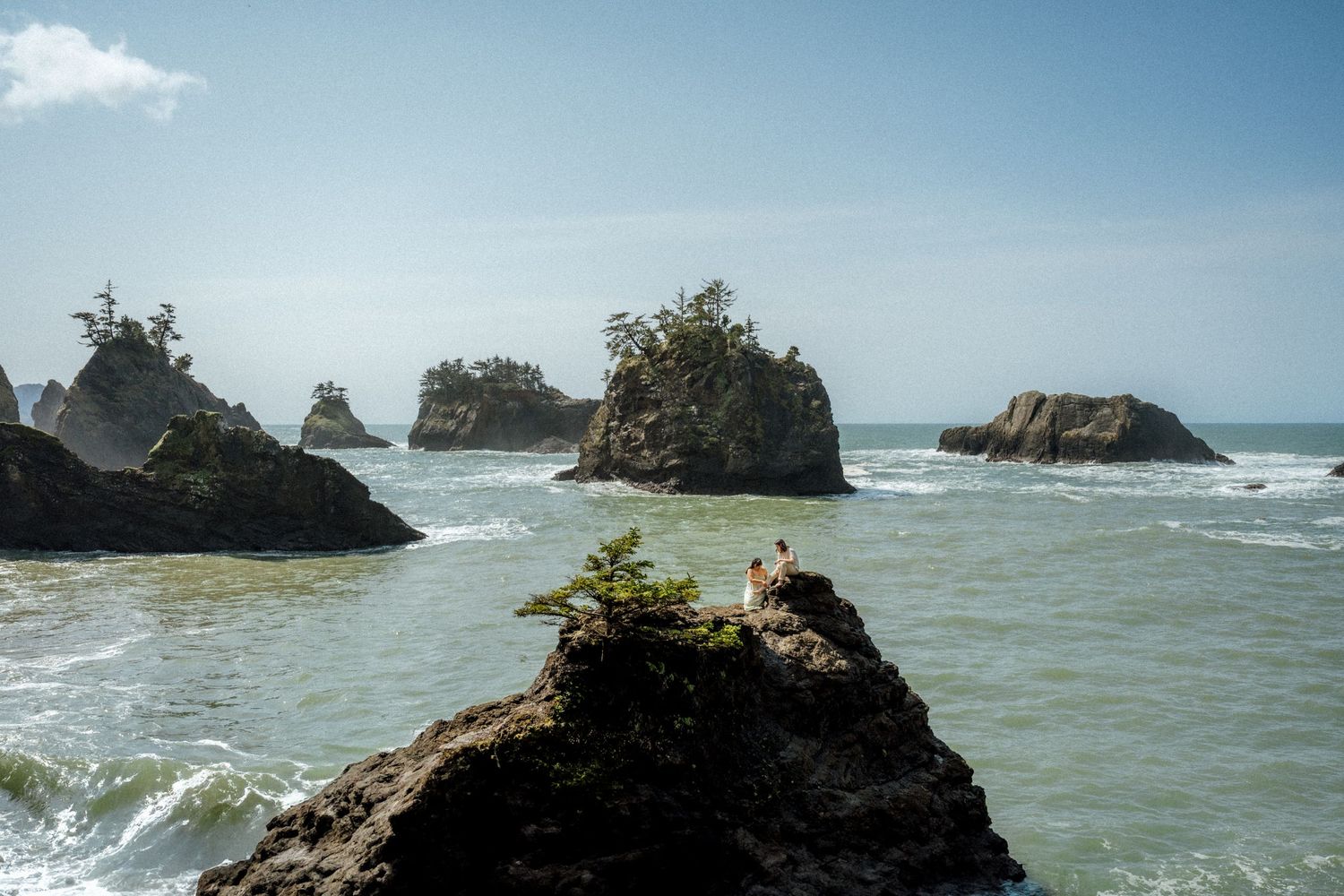 Panoramic view of rugged coastline with waves breaking against rocky formations.
