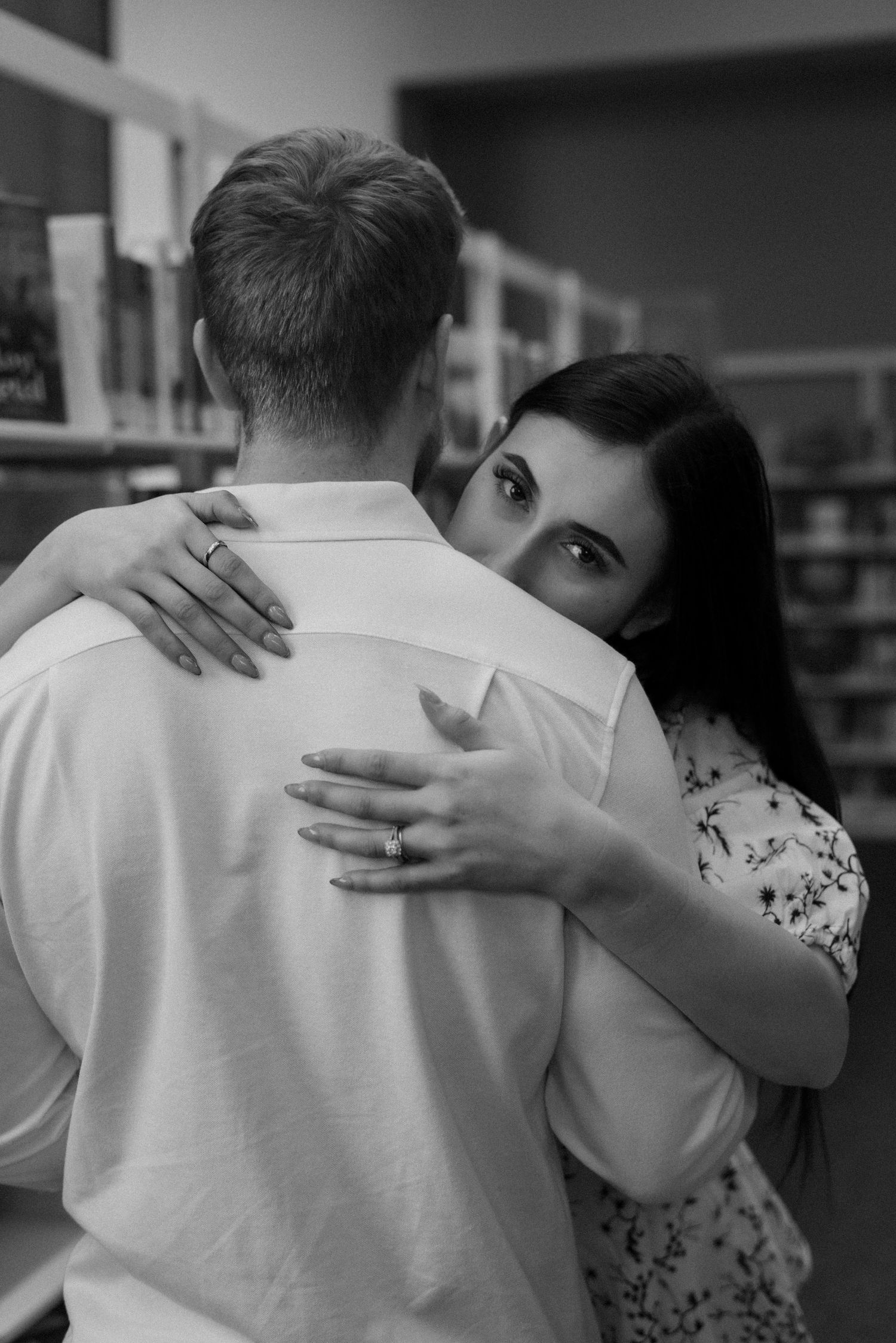 Intimate black and white sequence of a couple embracing in a library setting.