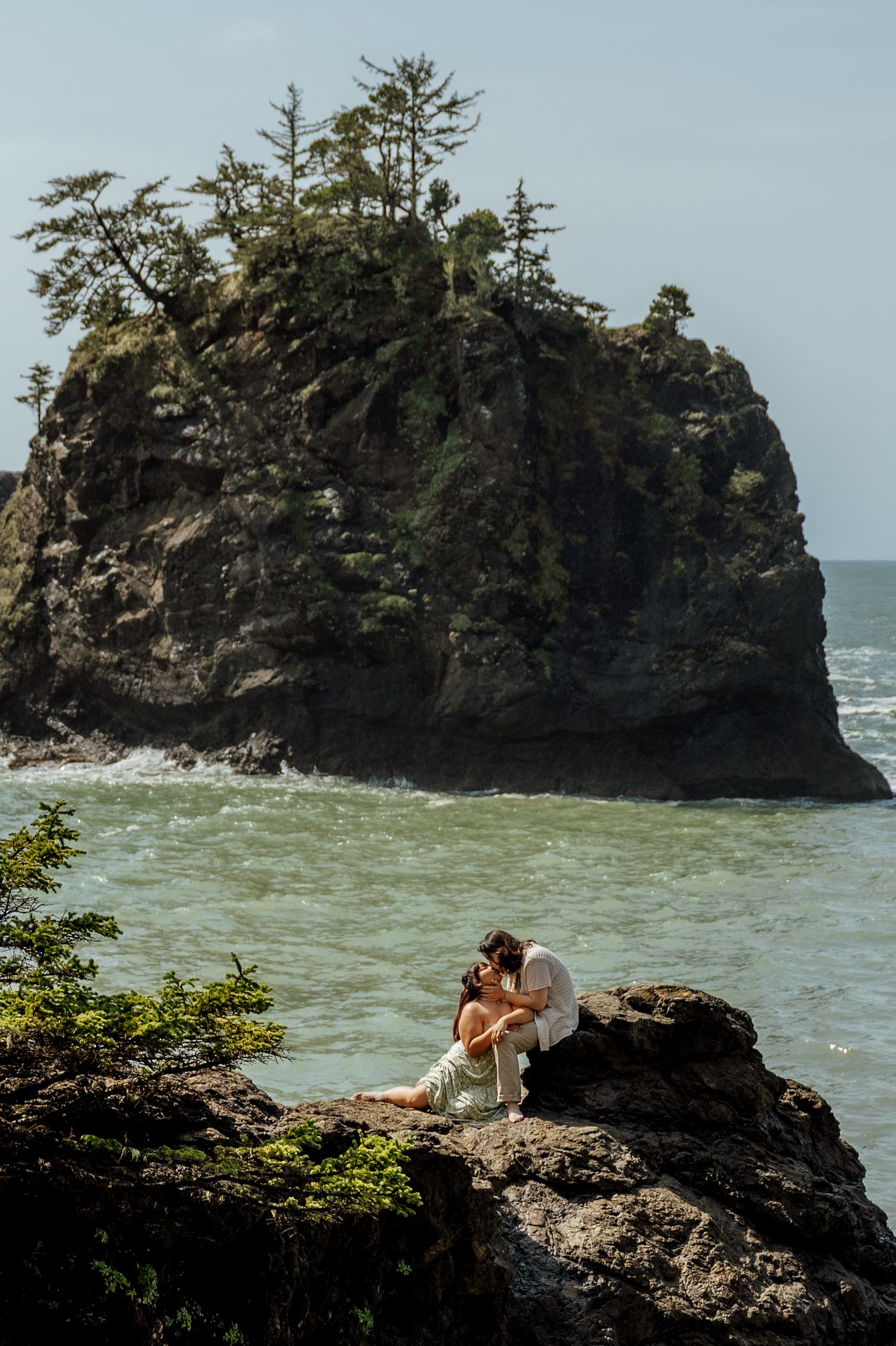 Rocky coastal cliffs rise dramatically from the ocean with waves crashing against the shore.