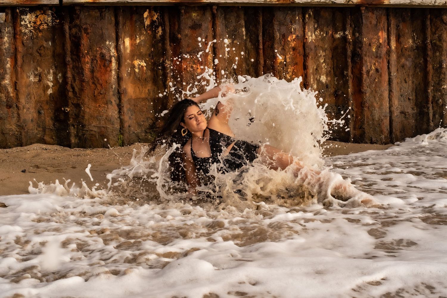 Ocean waves splash against wooden pier creating dynamic water patterns.