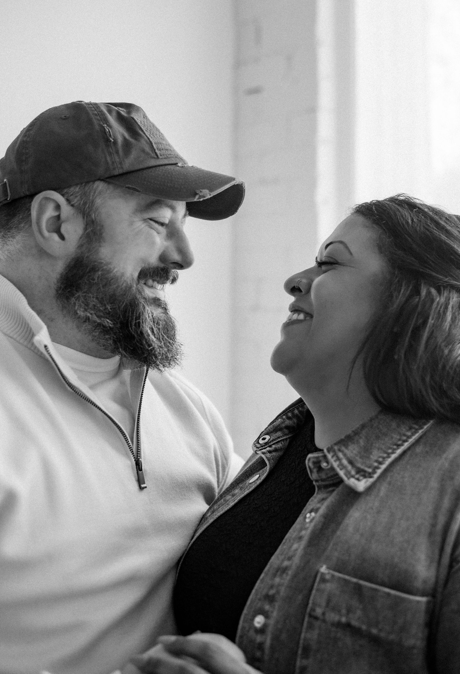 A joyful candid black and white photo showing a couple laughing together.