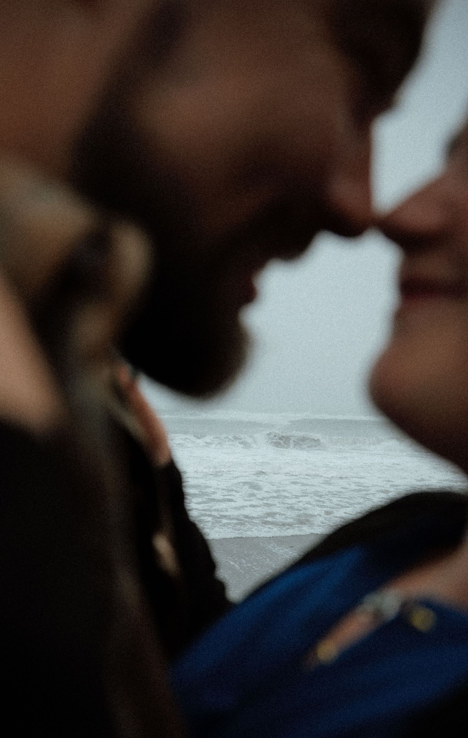 An intimate close-up silhouette of a couple with ocean waves in the background.