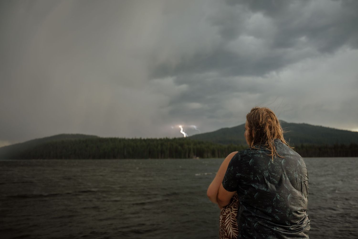 Moody panoramic landscape with stormy clouds over a mountain lake.