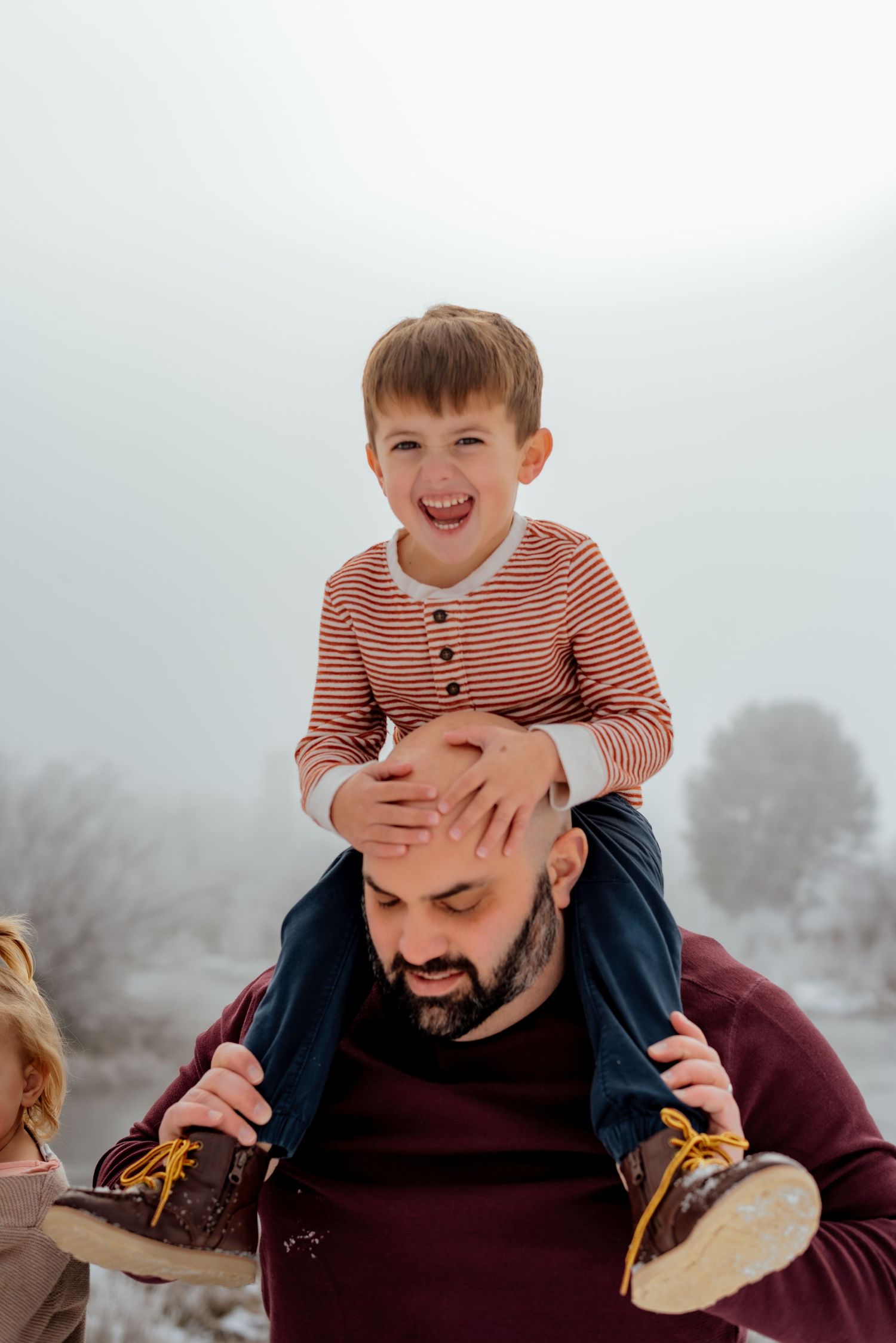 Playful winter family moments captured in snow with children riding piggyback.