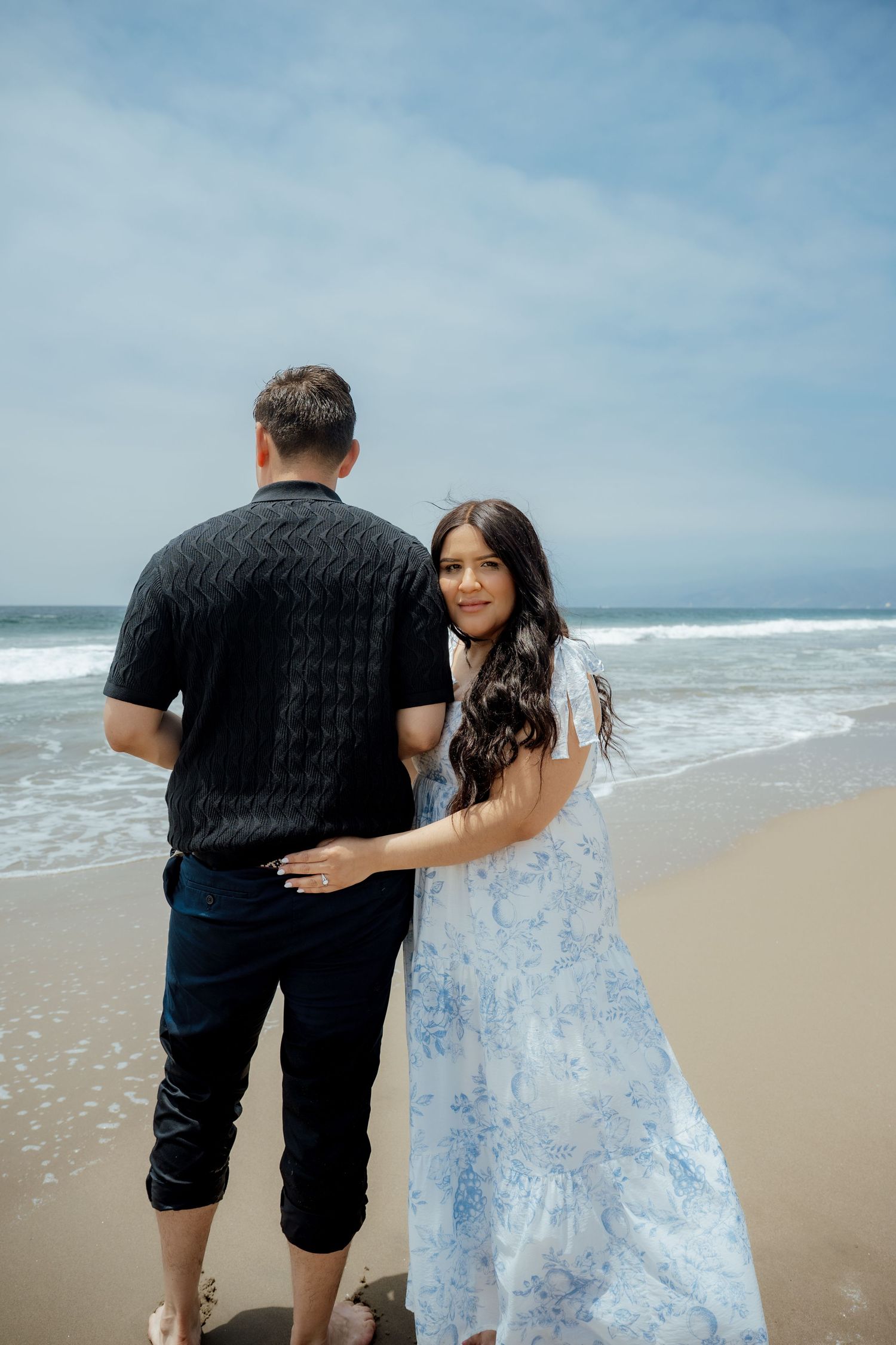 A couple shares an intimate moment while walking along the shoreline.