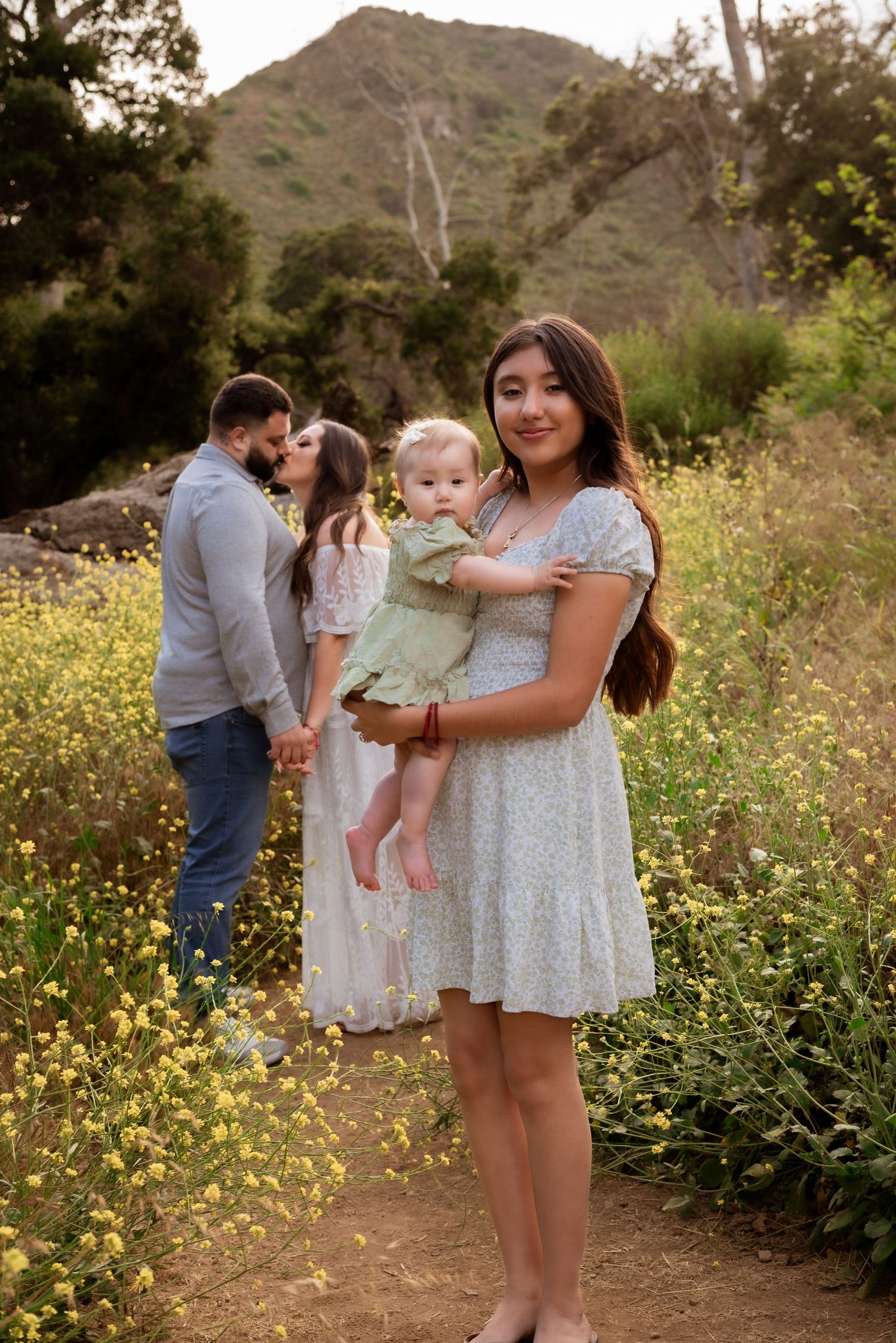 Sweet family moments captured in blooming wildflower meadow with mountain backdrop.