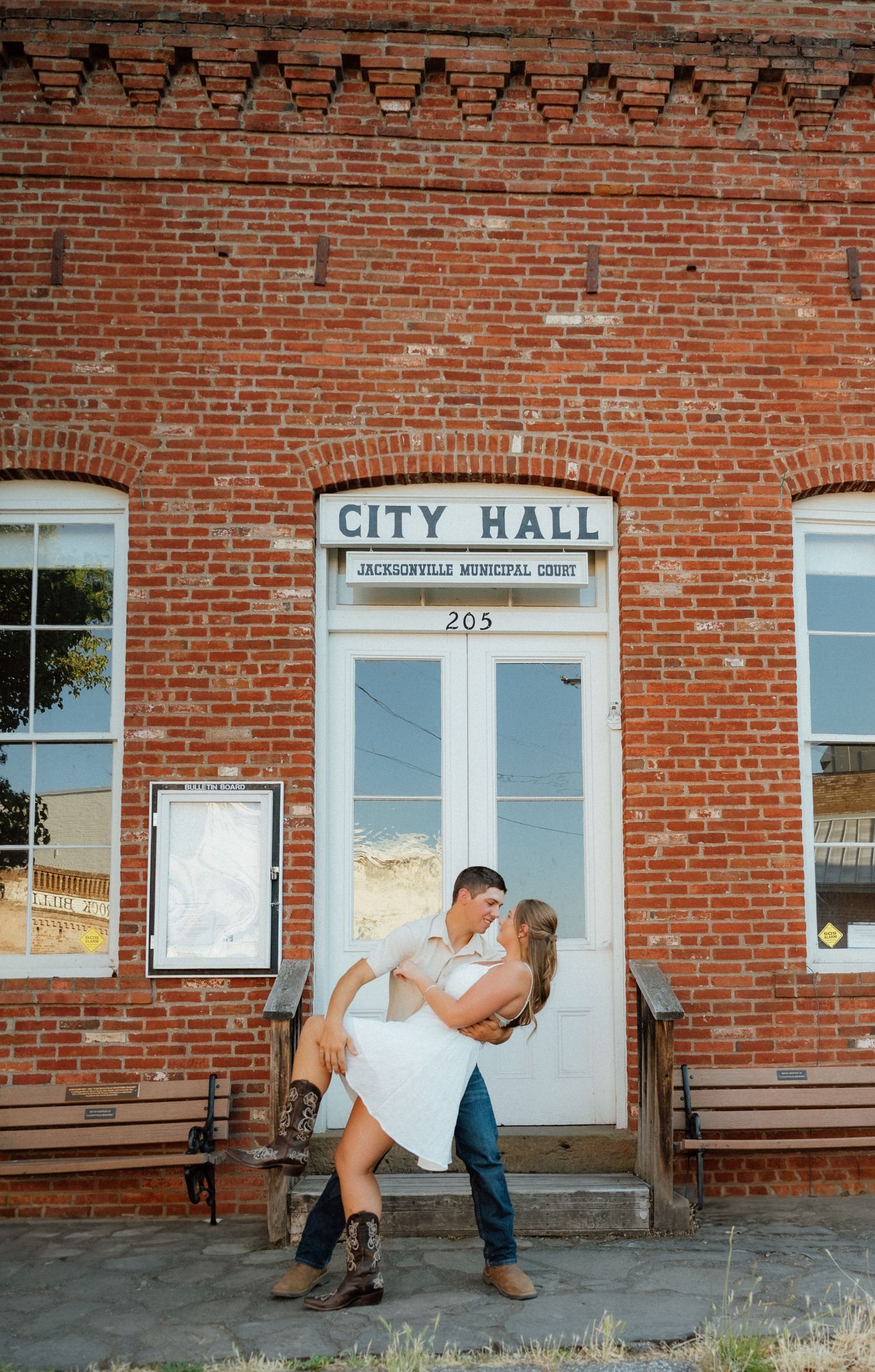 A series of romantic poses against a brick City Hall building exterior.
