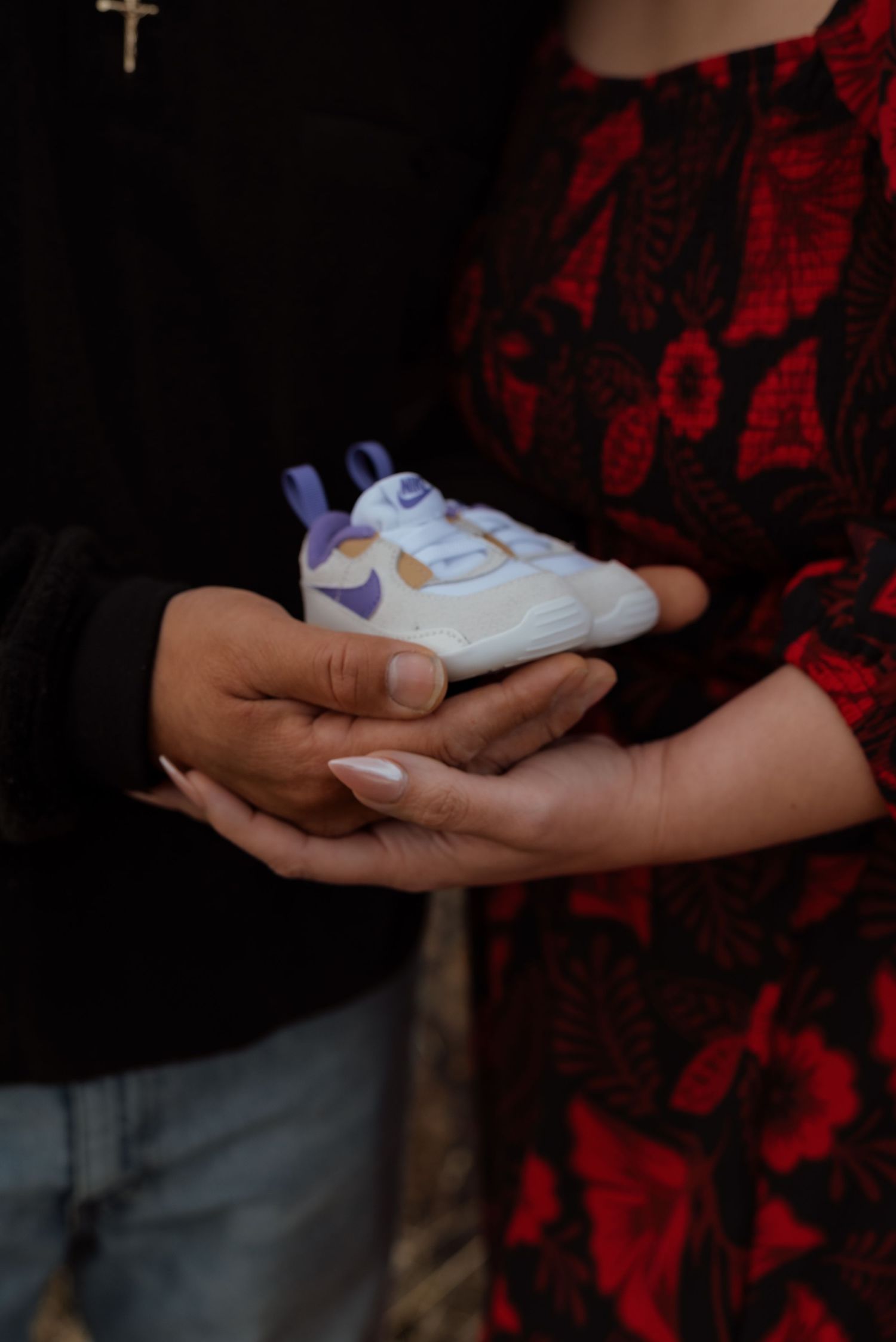 Close-up shots of hands holding small white baby shoes.