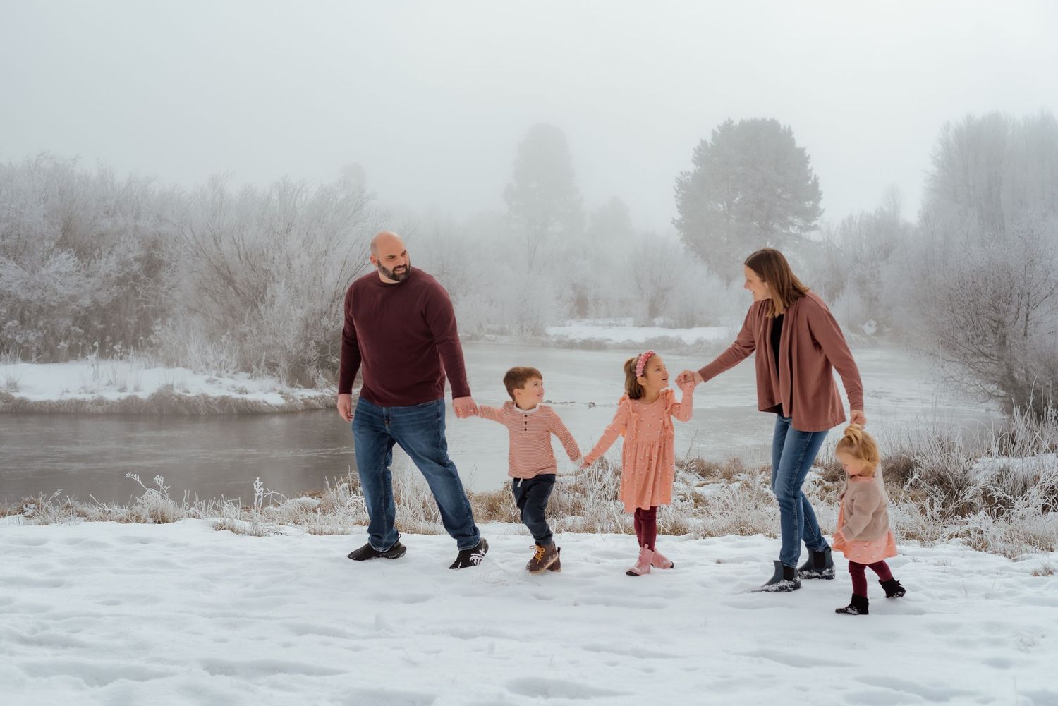 Candid family moments captured while walking through snowy winter landscape.