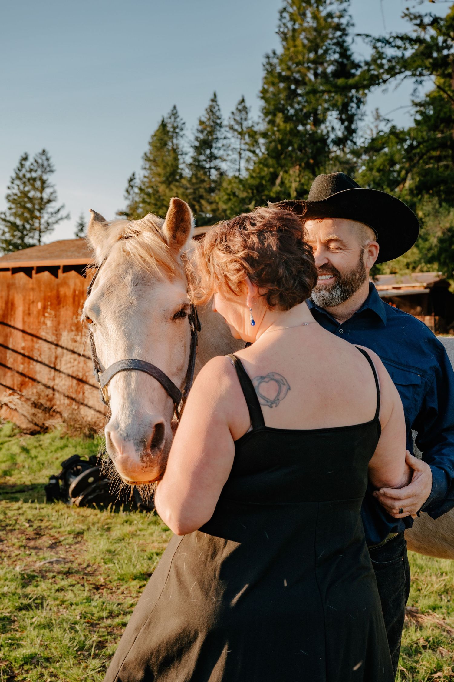 A beautiful white horse joins a couple for outdoor photos in a rustic setting.