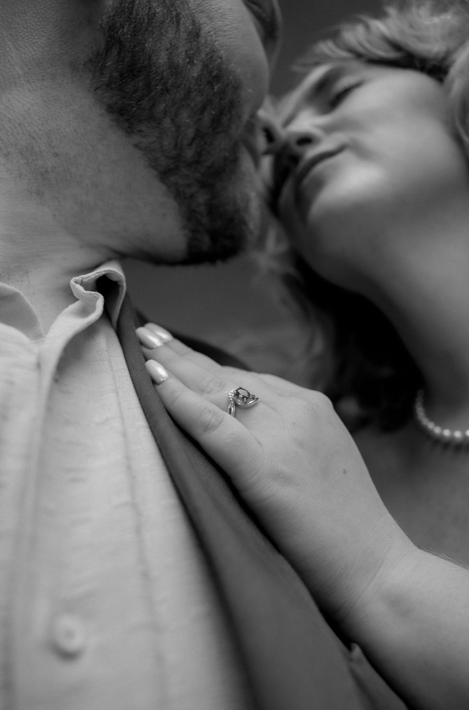 A romantic black and white close-up photo showing a tender kiss and an engagement ring.