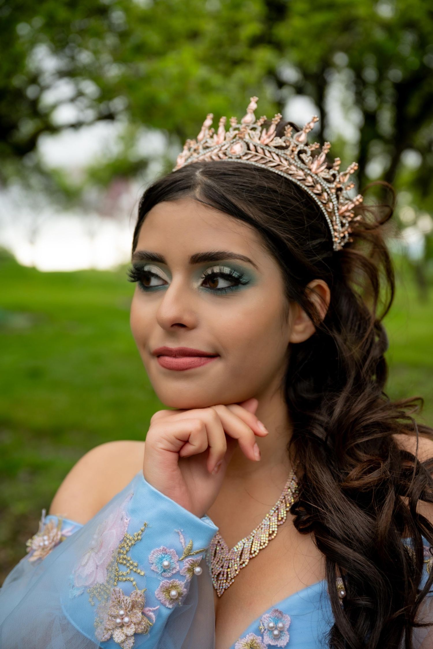 Ornate gold crown and dramatic eye makeup details in an outdoor portrait session.