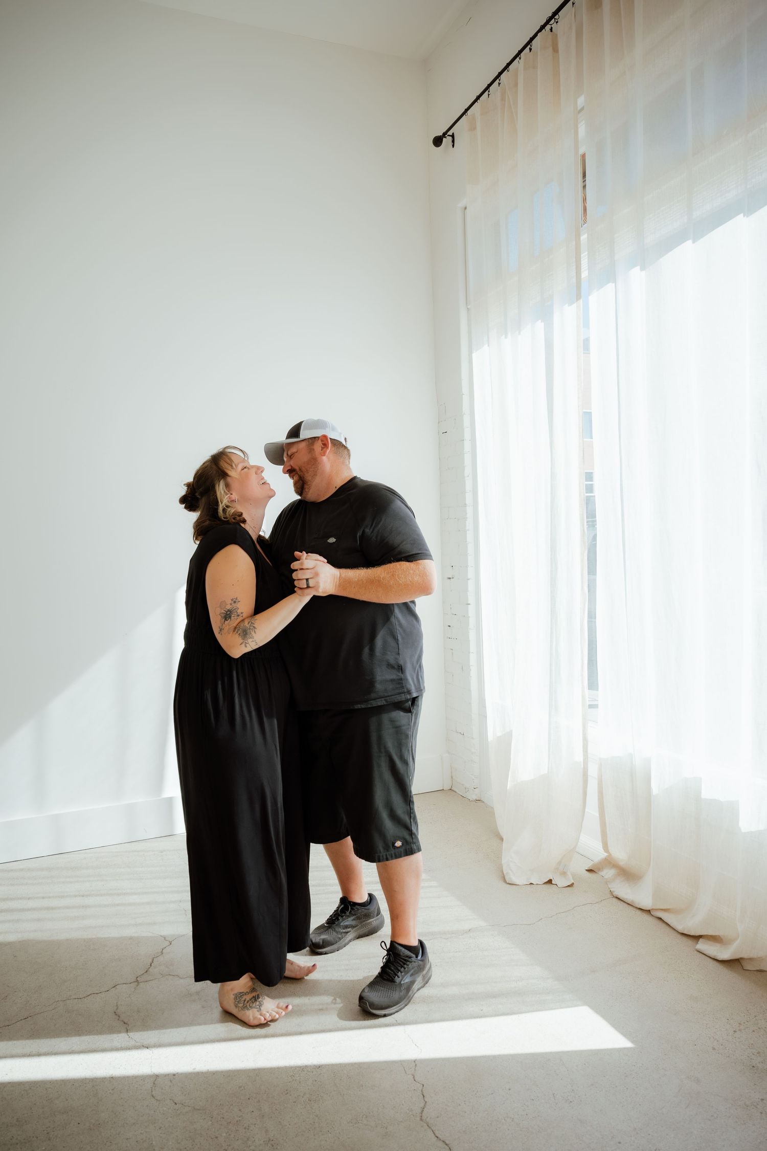 A couple shares an intimate moment in a bright white minimalist room.