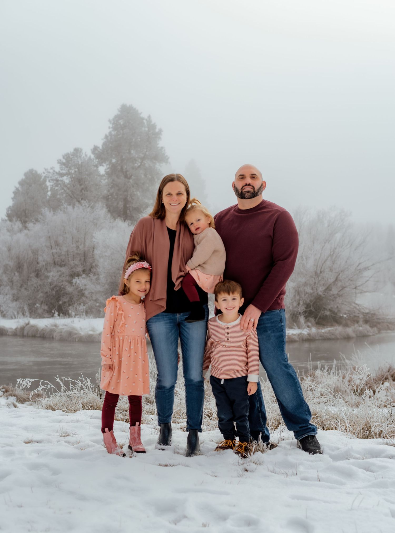 Family portrait in winter setting with snow covered ground and foggy background.