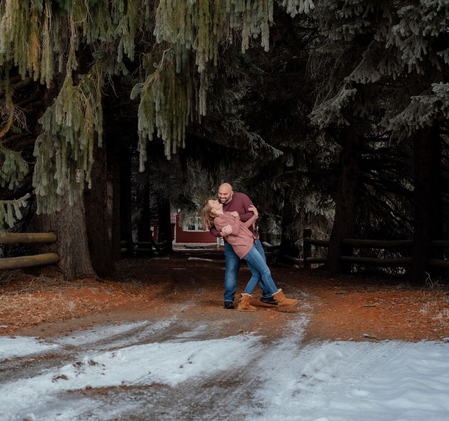 Two people share a playful moment in a winter forest scene with snow on the ground.