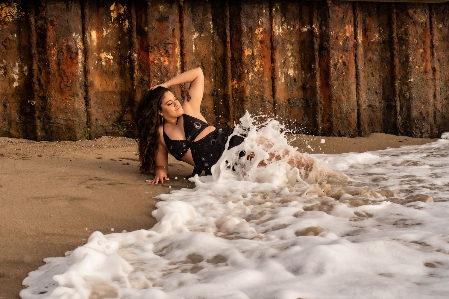 Waves crash dramatically against wooden structure creating white water spray.