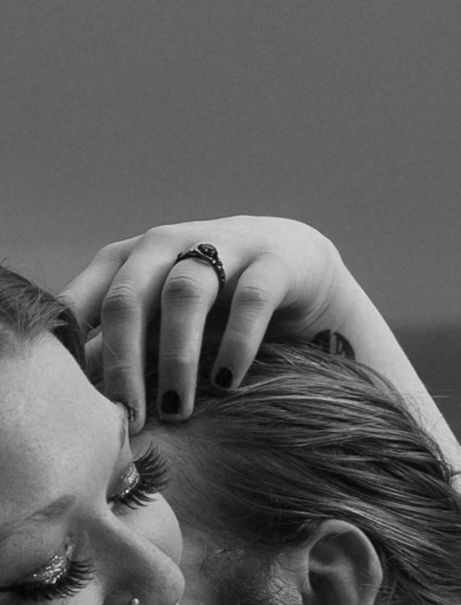 Intimate black and white artistic portrait showing a close-up side profile against a dark background.