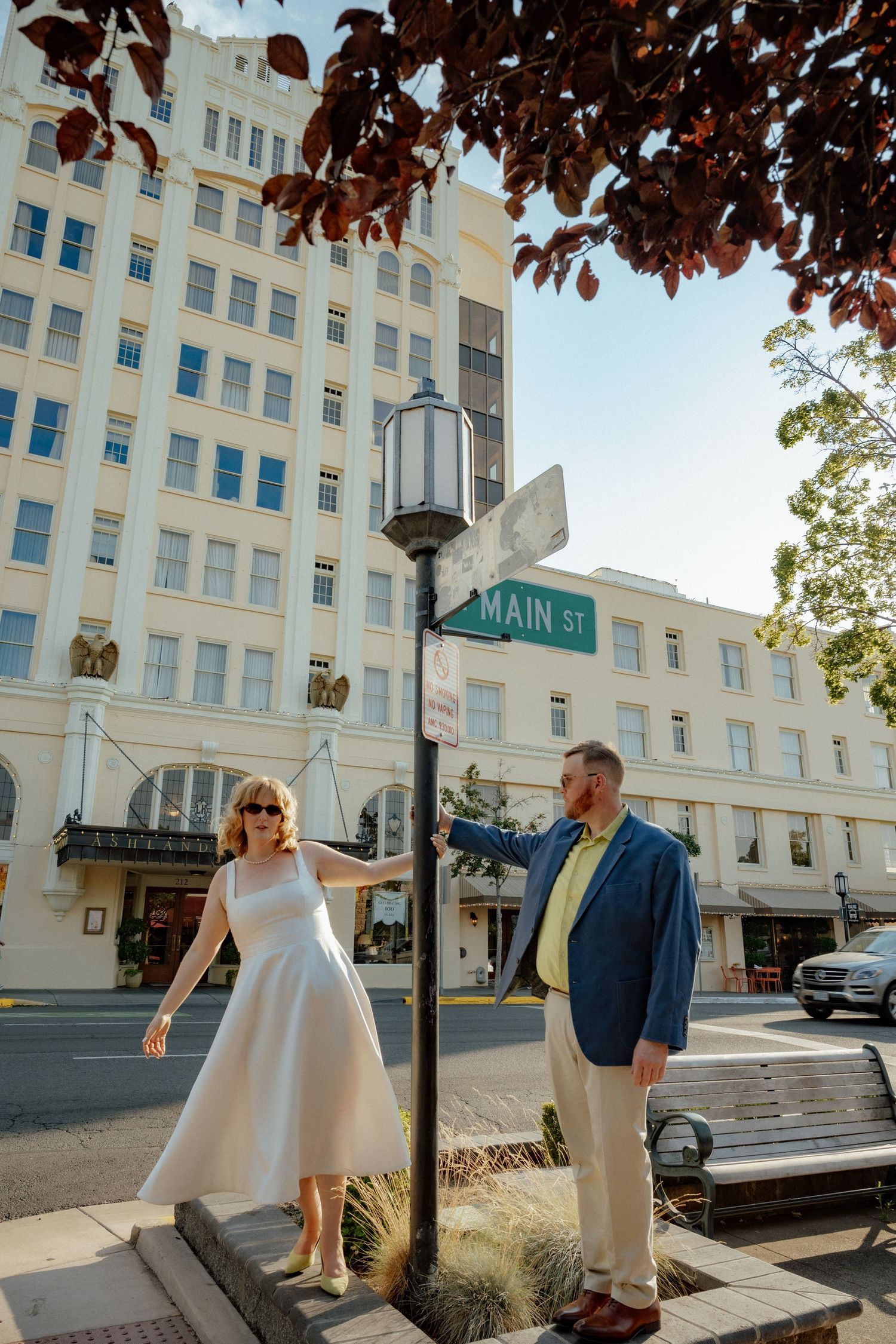 A couple poses by a vintage street lamp on Main Street in front of a historic building.