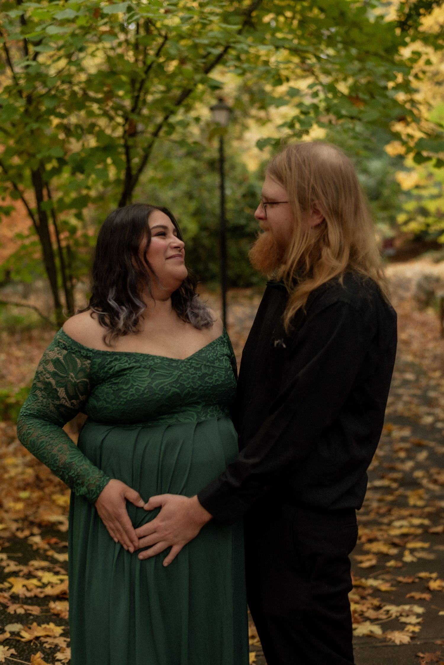 A couple shares an intimate moment in an autumn forest setting with yellow foliage.