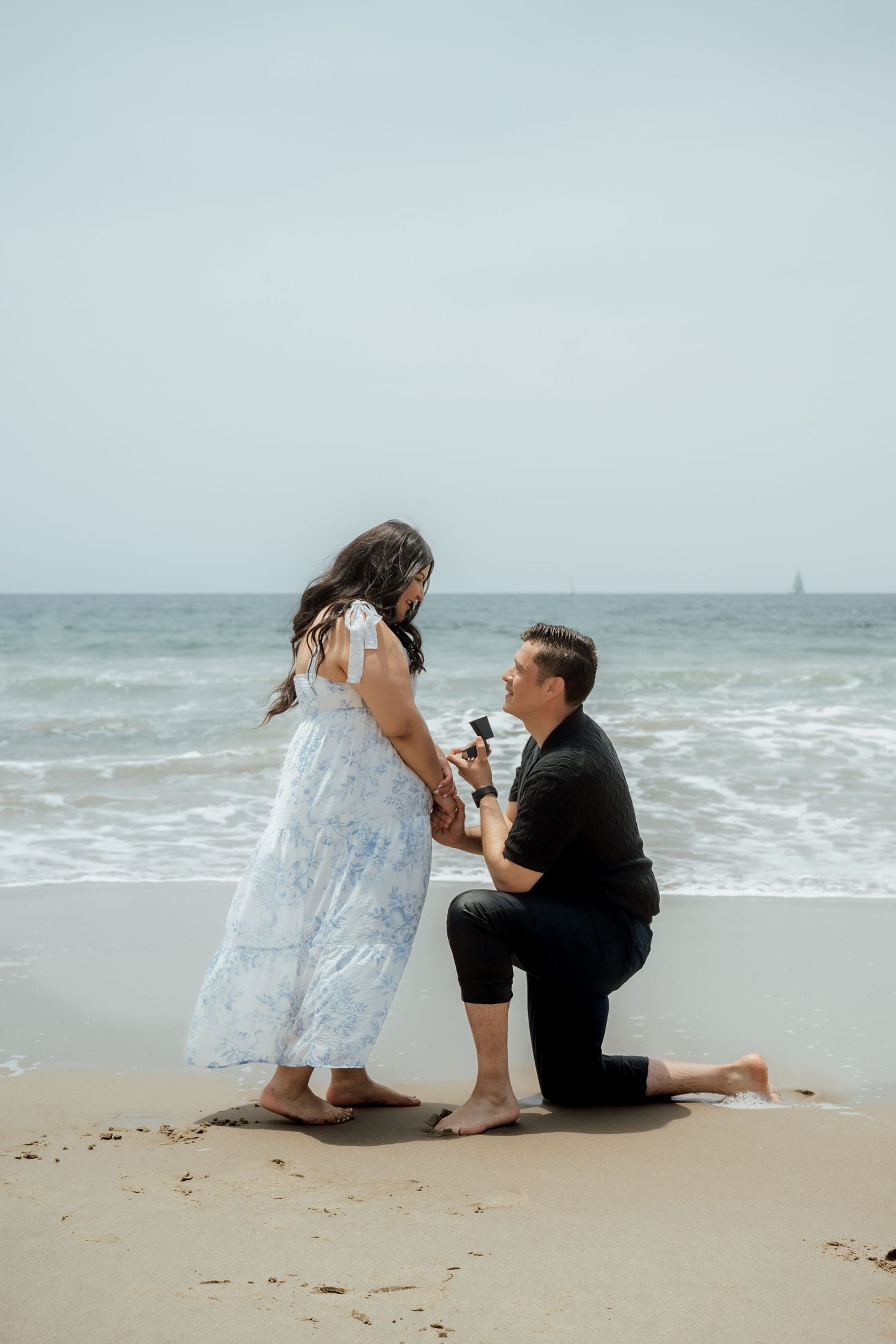 A romantic beach proposal scene with crashing waves in the background.