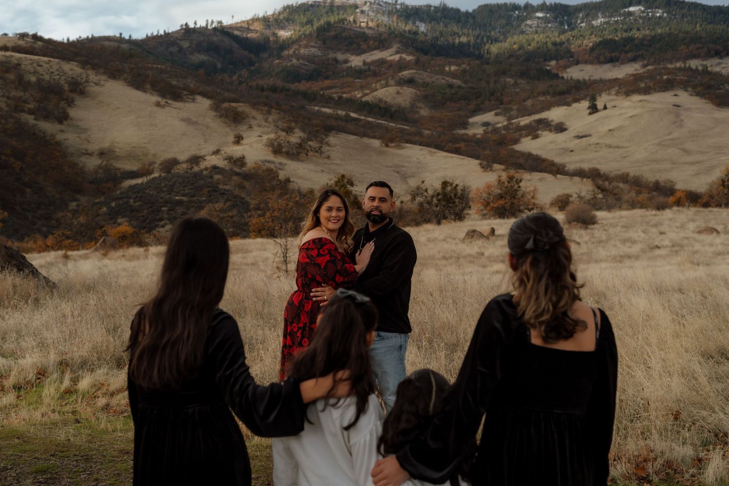Group photo session in a scenic mountain field during golden hour.