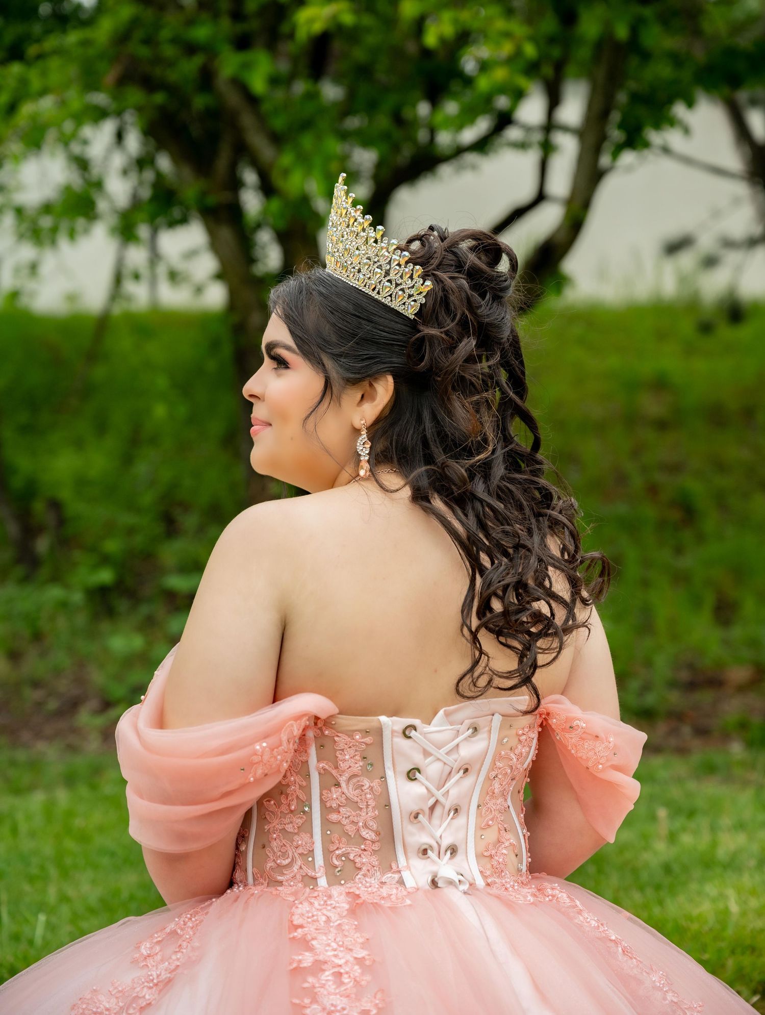 Back detail of a coral pink ballgown with lace-up corset photographed outdoors.