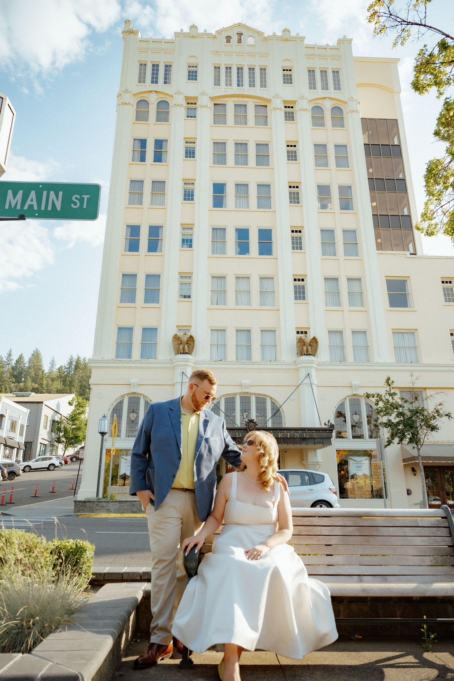 Couple sitting on a bench outside a historic white building on Main Street.