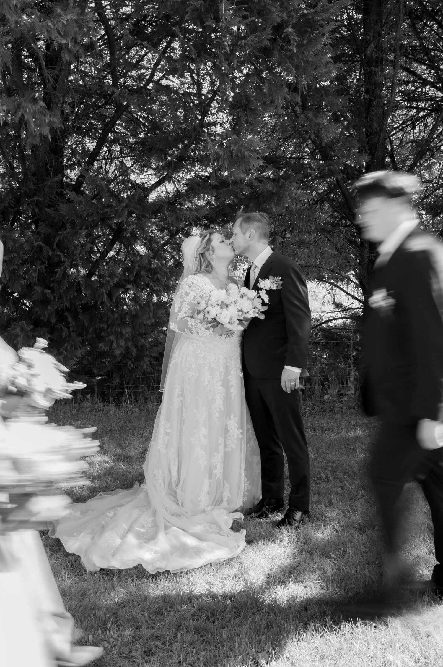 Black and white wedding photography capturing moments on a grassy outdoor setting.