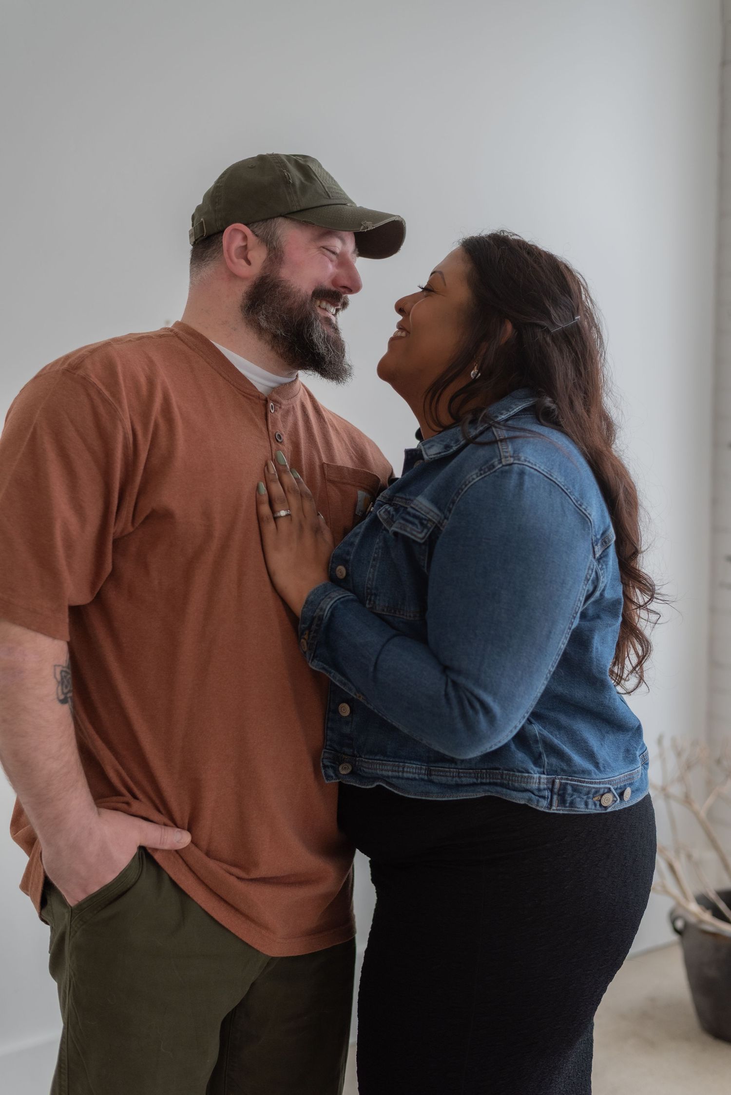 A couple shares a lighthearted moment against a white studio backdrop.