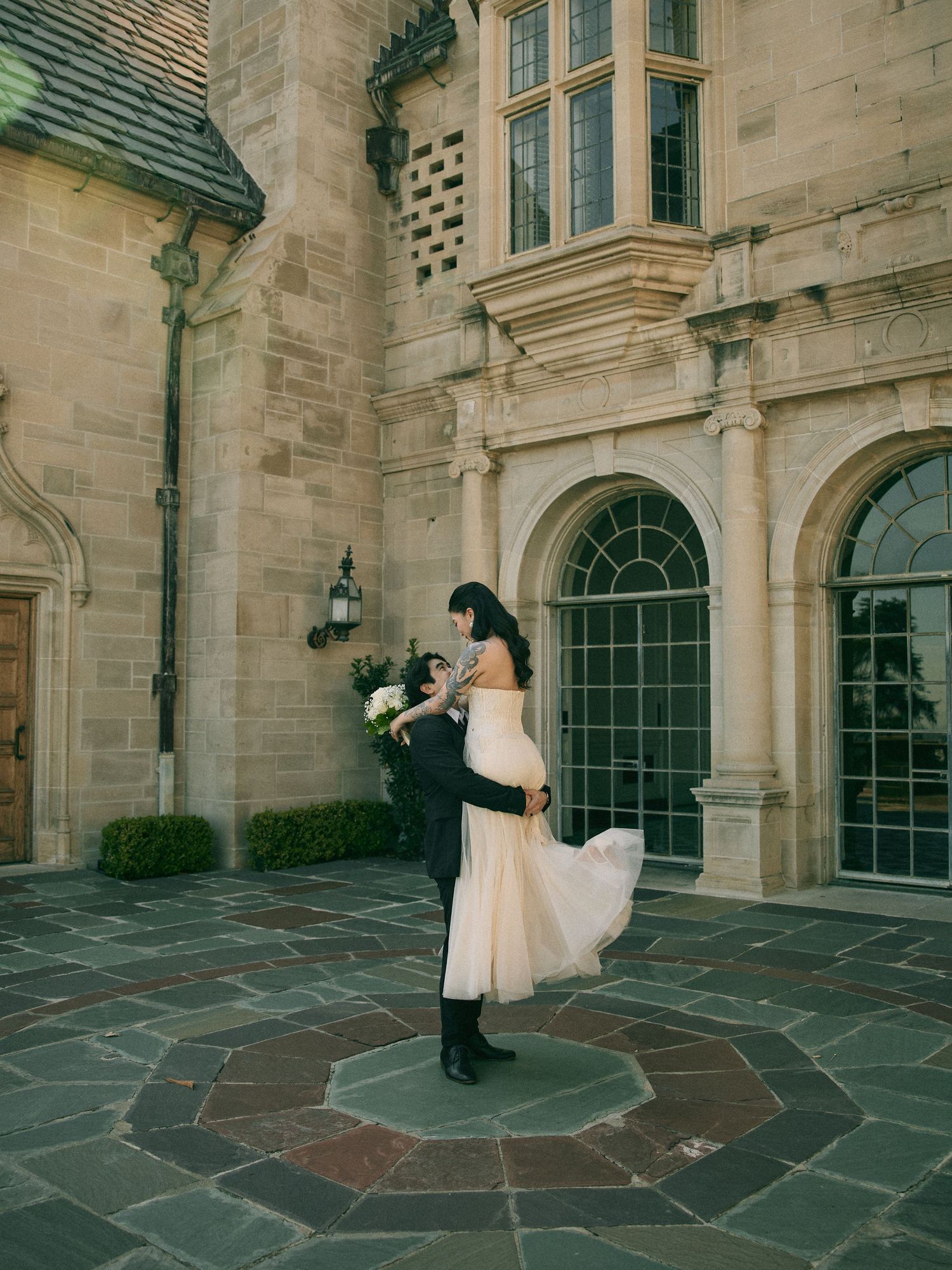 Bride swirling her dress in front of a European-style stone estate courtyard.