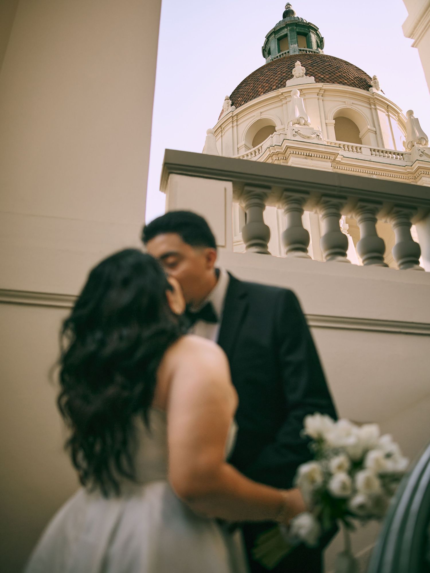 Romantic kiss in front of the historic Pasadena City Hall dome by Southern California wedding photographer.