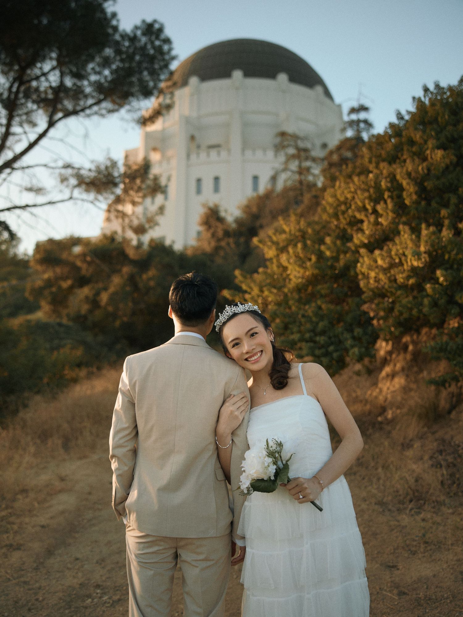 Sunrise engagement portraits framed by classic architecture and natural greenery at Griffith Observatory.