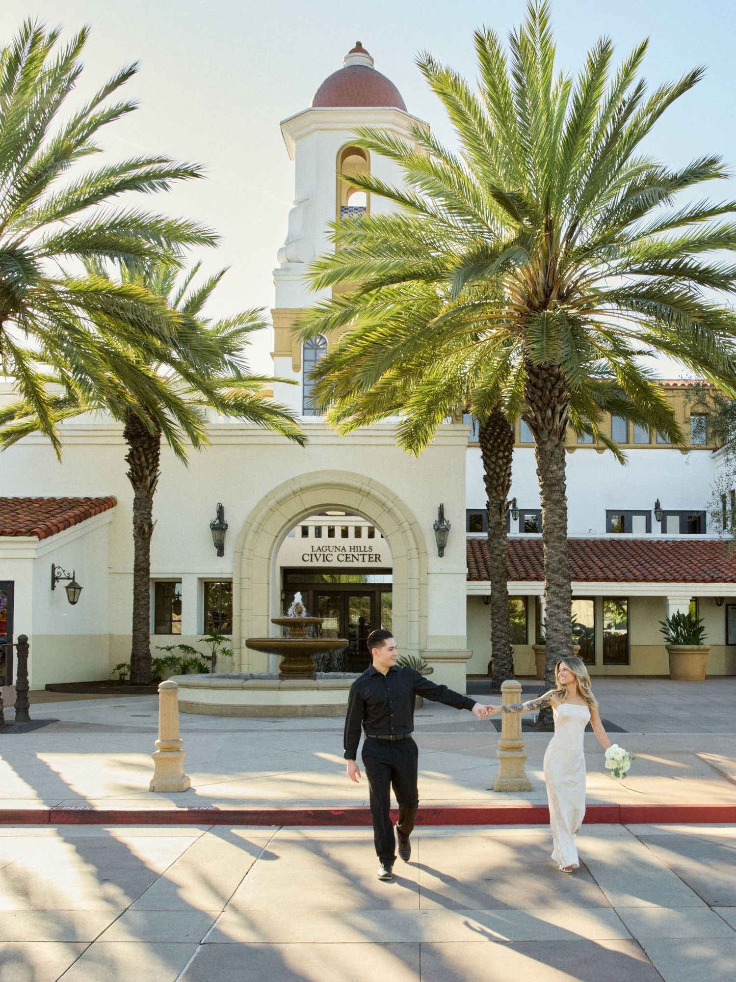 Romantic wedding couple walking outside Spanish architecture at Laguna Hills Civic Center.