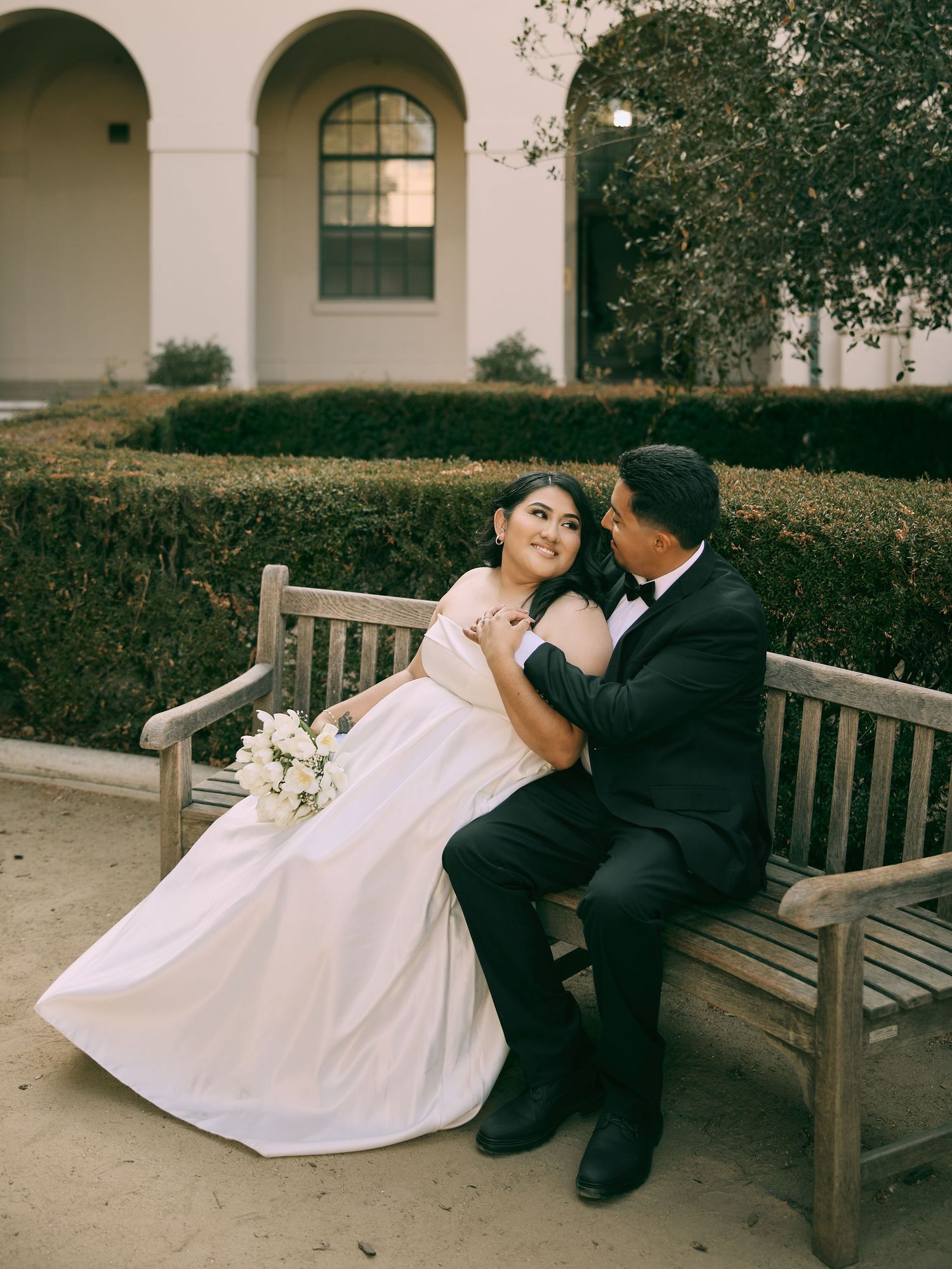 Bride and groom sitting together on a garden bench for intimate Pasadena City Hall wedding photos.